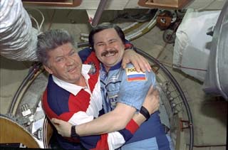 STS-91 mission specialist Valery Ryumin (left) greets Cosmonaut Nikolai Budarin at the docking module hatch.